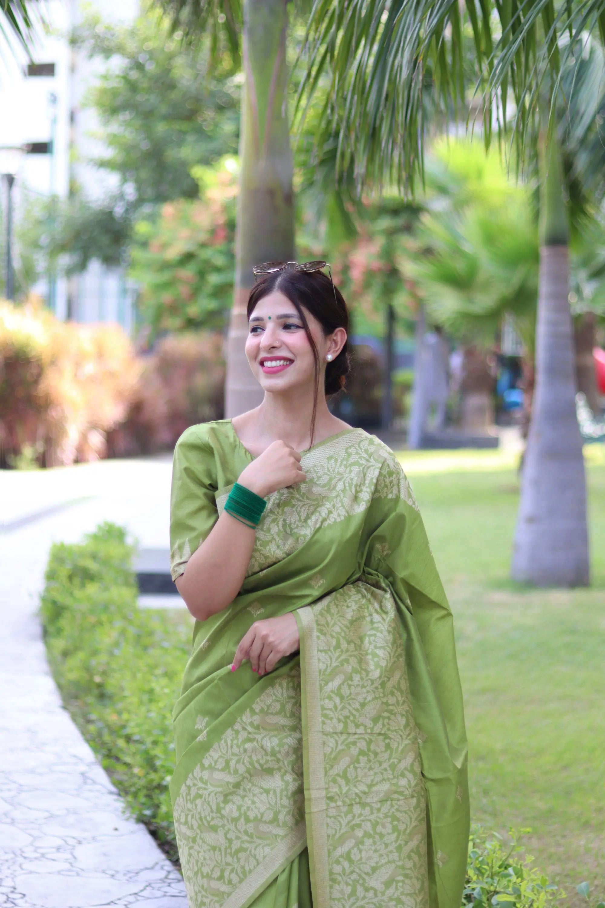 Woman wearing light pista traditional weaving saree posing gracefully in an outdoor garden setting
